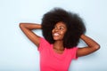 Close up happy young black woman smiling with hands behind head against blue background Royalty Free Stock Photo