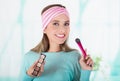 Close up of happy young woman holding a make up palette and doing crazy make-up in her face using a make up brush, in a