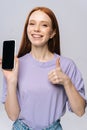 Close-up of happy young woman showing cell phone with black empty mobile screen and thumb-up gesture