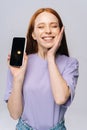 Close-up of happy young woman showing phone with black empty mobile screen, holding hand near face. Royalty Free Stock Photo