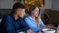 Close up of happy young woman sitting at table in restaurant talking with handsome man and typing on a laptop. Caucasian Royalty Free Stock Photo