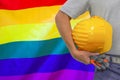 Hand of worker and yellow hard-hat on background flag of Rainbow Royalty Free Stock Photo