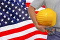 Hand of worker and yellow hard-hat on background flag of US Royalty Free Stock Photo