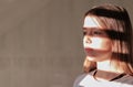 Close up hard light portrait of tween girl with stripe shadows on her face.