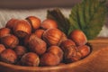 Close up of hazelnuts with green leaves in wooden bowl on rustic background Royalty Free Stock Photo