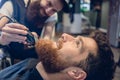 Close-up of the head of a man and the hand of a barber trimming