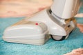 Close up of the head of a modern vacuum cleaner being used while vacuuming a thick pile white carpet Royalty Free Stock Photo