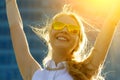 Close up head shot portrait of young woman with arms raised rejoicing summer