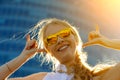 Close up head shot portrait of young woman wearing sunglasses. Happy girl standing under sunbeams and rejoicing summer. Blurred