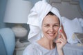 Close-up head shot smiling beautiful woman wrapped in towel applying toner Royalty Free Stock Photo