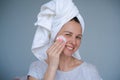 Close-up head shot smiling beautiful woman wrapped in towel applying toner Royalty Free Stock Photo