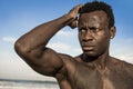 Portrait of young attractive and fit black African American man with strong muscular body posing cool model attitude on the beach