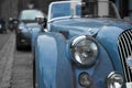 Close up of the headlight of a blue classic sport car, with blurred background