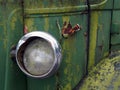 Close up of the headlight of an old abandoned truck with rusted green grille and panels Royalty Free Stock Photo