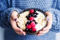 Close up of healthy organic breakfast. Child in woolen classic blue colored sweater holding bowl of of muesli and yoghurt with Royalty Free Stock Photo