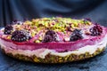 Close up of healthy raw cake with blackberries and pistachios flat lay on dark granite