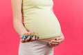 Close up of heap of blisters of pills in pregnant woman`s hand at colorful background with copy space. Healthcare and treatment