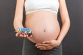 Close up of heap of blisters of pills in pregnant woman`s hand at colorful background with copy space. Healthcare and treatment