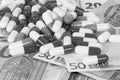 Close up of a heap of capsules lying on different euros in the studio black and white