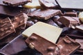 Close up of a heap of various chocolate pieces over dark wood background. Dark, milk, white and nuts chocolate bars. Royalty Free Stock Photo