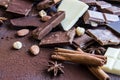 Close up of a heap of various chocolate pieces over dark wood background. Dark, milk, white and nuts chocolate bars. Cinnamon, sta