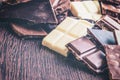 Close up of a heap of various chocolate pieces over dark wood background. Dark, milk, white and nuts chocolate bars. Copy space. Royalty Free Stock Photo