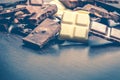 Close up of a heap of various chocolate pieces over dark wood background. Dark, milk, white and nuts chocolate bars. Copy space. Royalty Free Stock Photo