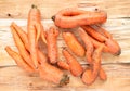 Close-up heap of washed non-standard ugly carrots on unusual natural wooden background.