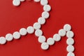 Close up of heart and cardiogram made of white pills over red background. Heart and cardiovascular disease, health and