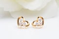 Close up of Heart shaped diamond gold earrings on the white ground