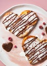 Close-up of heart-shaped sweet toasts topped with cream, chocolate and raspberry crumbles on a white and pink Royalty Free Stock Photo