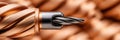 Close-up of helically wound copper wire with a metallic drill bit, representing industrial tools and precision engineering Royalty Free Stock Photo