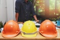 Close up of a helmets on the desk with architect working with blueprint construction project in home office Royalty Free Stock Photo