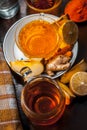 Close up of a herbal tea  consisting of apple juice,lemon,ginger and warm water in a transparent cup on a wooden surface in dark G Royalty Free Stock Photo