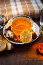 Close up of a herbal tea  consisting of apple juice,lemon,ginger and warm water in a transparent cup on a wooden surface in dark G Royalty Free Stock Photo