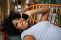 Close-up high-angle view of cheerful African young woman talking on smartphone lying on comfortable couch having Royalty Free Stock Photo