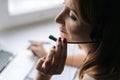 Close-up high-angle view of female operator talking using headset and consulting client sitting at window sill with Royalty Free Stock Photo