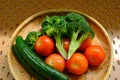 Close up high angle view of a group of fresh vegetables produce drying in bamboo sieve after being washed visible water droplets Royalty Free Stock Photo