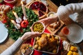 Close-up high-angle view of unrecognizable young woman and man passing delicious food sitting at festive Christmas table Royalty Free Stock Photo