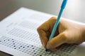 Close up of high school or university student holding a pen writing on answer sheet paper in examination room. College students an