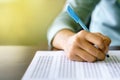 Close up of high school or university student holding a pen writing on answer sheet paper in examination room. College students an Royalty Free Stock Photo