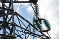 Close-up on a high voltage electric antenna, metal details and insulator chain, in a blue, cloudy sky