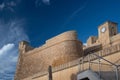 Close-up of the high wall of the historic citadel on Gozo in Malta. The strong walls tower high up. The sky is blue with light-