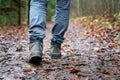 Close up of hiker walking down the wet forest path. Person with dirty hiking shoes on the footpath outdoors Royalty Free Stock Photo