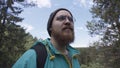 Close up of hipster hiker observing the the green valley on blue cloudy sky background. Stock footage. A bearded man