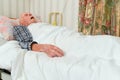 Elderly infirm man lying asleep in bed after being discharged from hospital