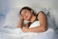 Close-up of Hispanic woman sleeping profoundly in white sheets at night