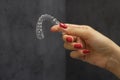 Close-up of holding dental aligner in women`s hand over Grey background