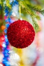 Close-up of holiday ornament for celebration Happy New Year. Shining red Christmas ball hanging on branch of Xmas pine Royalty Free Stock Photo