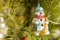 Close up of holidays location with snowman toy and garlands on green Christmas tree Royalty Free Stock Photo